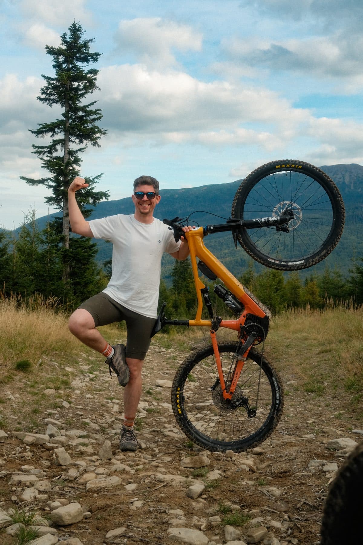 Uczestnik campu unosi rower MTB na górskim szlaku